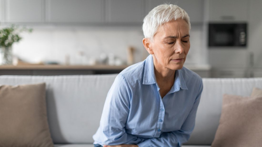 Žena si drží podbřišek, bolest při zánětu močových cest
