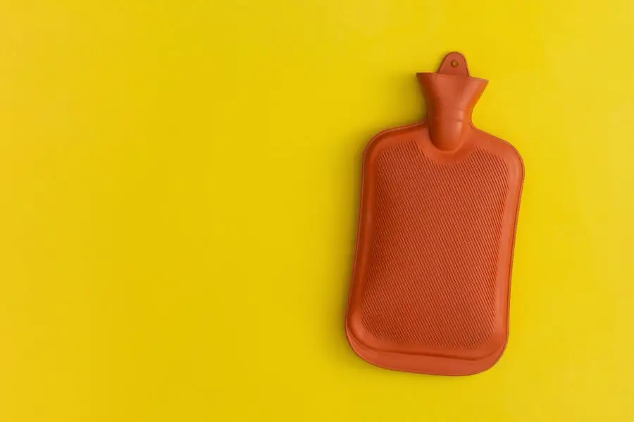грелка с горячей водой на желтом фоне