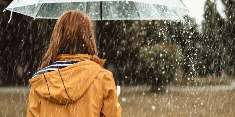 Frau geht mit Regenschirm im Regen spazieren - Symbolbild für Unterleibsschmerzen ohne Periode